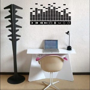 May include: A white desk with a black laptop, a black lamp, and a white chair. The wall behind the desk has a black and white music themed decal with sound waves and music player controls.