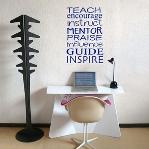 May include: A white desk with a laptop, a lamp, and a chair. The wall behind the desk has a blue vinyl decal with the words "TEACH, ENCOURAGE, INSTRUCT, MENTOR, PRAISE, INFLUENCE, GUIDE, INSPIRE".