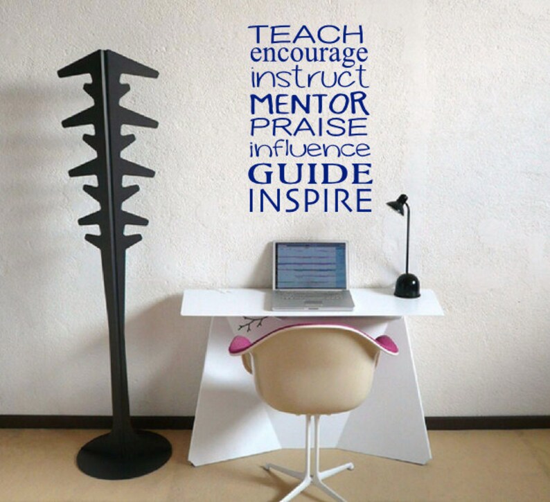 May include: A white desk with a laptop, a lamp, and a chair. The wall behind the desk has a blue vinyl decal with the words "TEACH, ENCOURAGE, INSTRUCT, MENTOR, PRAISE, INFLUENCE, GUIDE, INSPIRE".