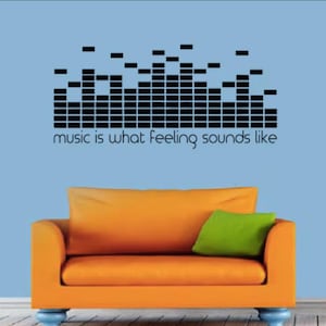 May include: A black and white graphic of a sound wave with the text "music is what feeling sounds like" on a light blue wall above an orange couch with a green pillow.
