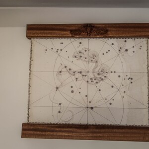 May include: A framed black and white illustration of a constellation with a grid pattern and a decorative design at the top of the frame.