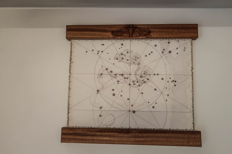 May include: A framed black and white illustration of a constellation with a grid pattern and a decorative design at the top of the frame.