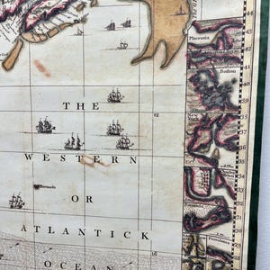 Puede incluir: Un mapa antiguo del Oc&eacute;ano Occidental o Atl&aacute;ntico, con una cuadr&iacute;cula de l&iacute;neas de longitud y latitud. El mapa muestra las costas de Am&eacute;rica del Norte y partes de Europa. El mapa est&aacute; impreso en papel y tiene un esquema de color marr&oacute;n, verde y rojo.