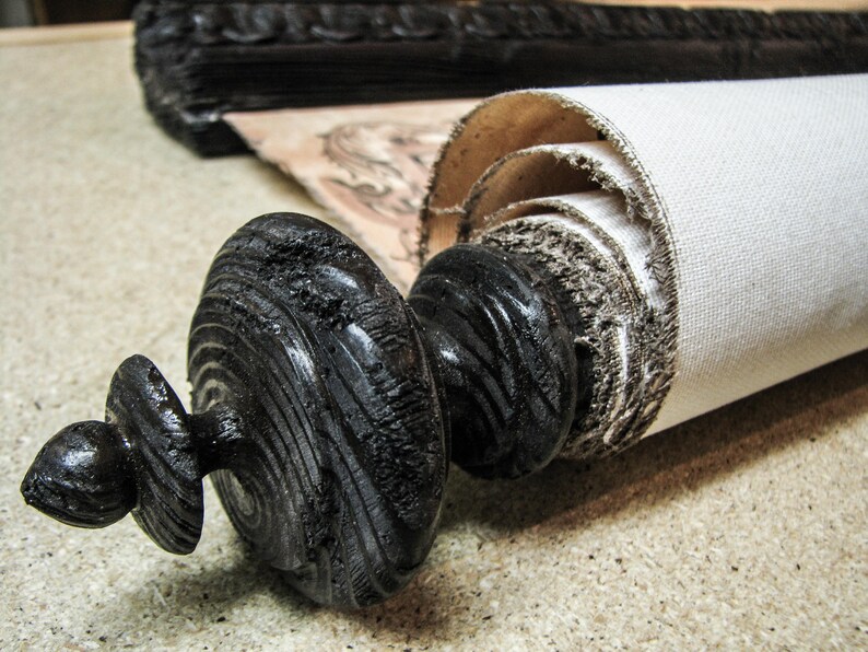 Handcrafted black wooden finial securing a rolled vintage canvas world map. Decorative scroll rod highlights rustic craftsmanship and antique-inspired wall décor for offices, libraries, and studies.