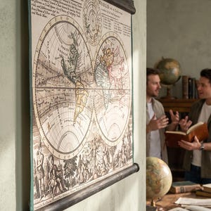 May include: A vintage-style wall map featuring a double-hemisphere world projection with aged paper tones, dark wooden hanging rods at the top and bottom, and detailed cartographic illustrations including text titled A New Map of the WHOLE.