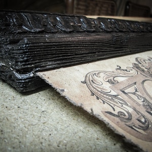 Macro view of a handcrafted Victorian-style wooden map hanger with carved detailing and black stained finish beside premium canvas. Artisan scroll frame for vintage world map wall art and classic home décor.