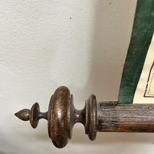 Puede incluir: Primer plano de un soporte de rollo de madera con un acabado marr&oacute;n oscuro. El soporte tiene un remate decorativo y una superficie acanalada.