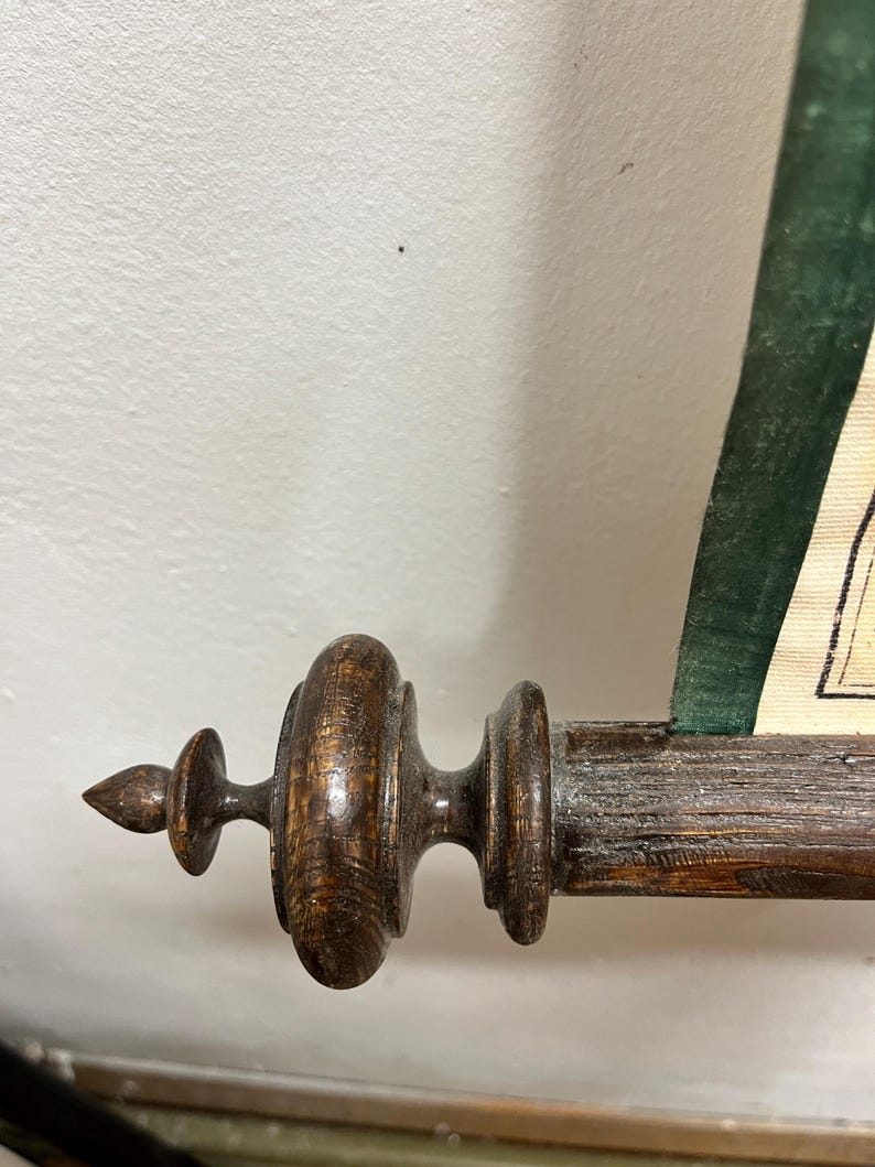 Puede incluir: Primer plano de un soporte de rollo de madera con un acabado marr&oacute;n oscuro. El soporte tiene un remate decorativo y una superficie acanalada.