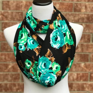 May include: A black infinity scarf with a floral pattern featuring teal, white, and brown flowers.