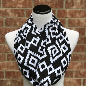 May include: A black and white infinity scarf with a geometric pattern. The scarf is made of a soft, stretchy fabric and is perfect for adding a touch of style to any outfit.