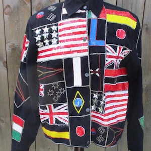 May include: Black jacket with a patchwork design featuring various flags, including the American flag, Union Jack, and others. The jacket has a collared neckline and button-down front. The flags are embellished with sequins.