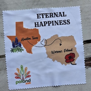 Puede incluir: Cuadrado de tela blanca con un mapa de Texas y Polonia, conectados por una línea punteada. El texto "ETERNAL HAPPINESS" está encima de los mapas. El mapa de Texas tiene una flor de lupino y el texto "Houston, Texas". El mapa de Polonia tiene una amapola roja y el texto "Warsaw, Poland".