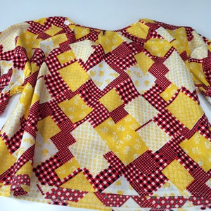 Puede incluir: Una blusa de manga abullonada con estampado de patchwork amarillo y rojo.