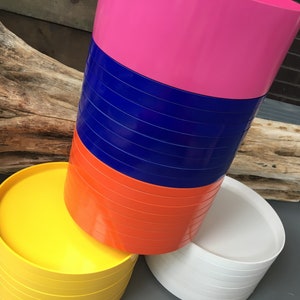 以下が含まれることがあります： 黄色、オレンジ、青、白のカラフルな丸いトレイが積み重ねられています。トレイは滑らかで光沢のある素材で作られており、スナックや飲み物を提供するのに最適です。