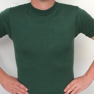 Puede incluir: Una camiseta de manga corta de color verde oscuro con cuello redondo.