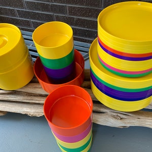 以下が含まれることがあります： カラフルな積み重ね可能なボウルとプレートのセット。ボウルは黄色、緑、紫、オレンジ。プレートは黄色、オレンジ、ピンク、緑、紫です。