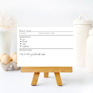 May include: A blank recipe card with the word "Recipe" at the top, with lines for "Makes", "Prep/Cook Time", "Ingredients", and "Instructions". The card is on a small wooden easel.