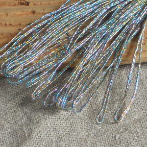 Pode incluir: Um feixe de fio met&aacute;lico iridescente azul e prata. O fio &eacute; brilhante e tem um brilho sutil.