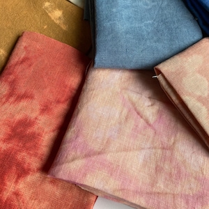 Op de afbeelding: Vier stofstalen in verschillende tinten bruin, rood, roze en blauw. De stof is een linnenmix en heeft een natuurlijke, textuurrijke uitstraling.