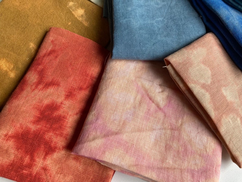 Op de afbeelding: Vier stofstalen in verschillende tinten bruin, rood, roze en blauw. De stof is een linnenmix en heeft een natuurlijke, textuurrijke uitstraling.