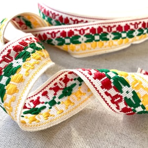 May include: White cotton ribbon with a repeating pattern of red, green, and yellow geometric shapes.
