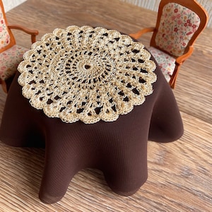 May include: A brown table with a gold crochet doily on top. Two chairs with floral patterned upholstery are placed around the table.