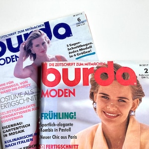 May include: Two vintage Burda Moden magazines are displayed, featuring cover models. The magazines have the text "Burda Moden" in large letters. One cover has the text "Frühling!" and the other has the text "Juni '92".