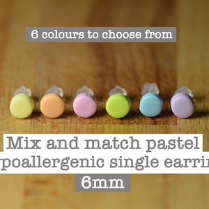 May include: Six pastel-coloured, hypoallergenic single earrings, each 6mm in diameter, are displayed. The earrings are in yellow, orange, pink, green, blue, and purple. The text above reads "6 colours to choose from".