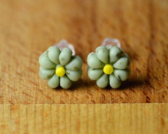 Pendientes pequeños con forma de flor en postes de plástico.