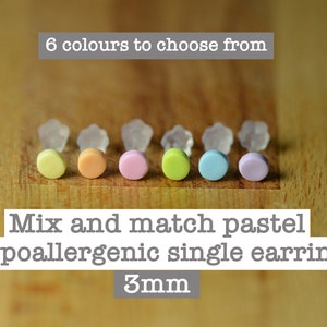 May include: Six pastel coloured hypoallergenic single earrings, each 3mm in diameter. The colours are yellow, orange, pink, green, blue, and purple.