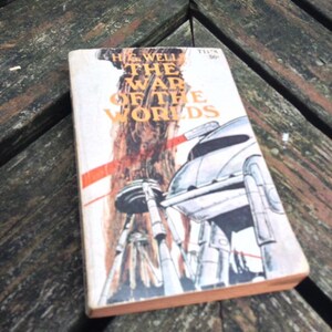 May include: A vintage paperback copy of "The War of the Worlds" by H.G. Wells. The cover features an illustration of a Martian tripod.