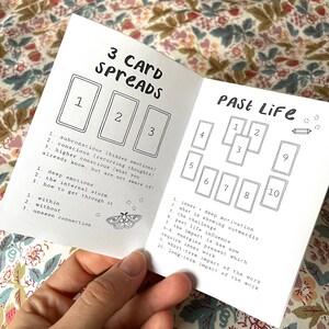 May include: A black and white booklet with the title "3 Card Spreads" and a section titled "Past Life" with a 10-card spread layout. The booklet includes instructions for each card position.