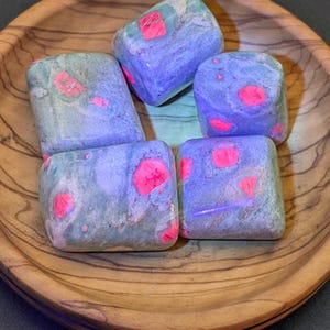 May include: Five tumbled stones with a green and blue base and pink accents. The stones are in a wooden bowl.