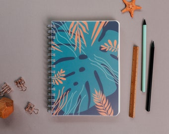 May include: A teal blue spiral bound notebook with a tropical leaf design. The notebook is surrounded by office supplies, including a wooden ruler, two pencils, and three gold binder clips. A starfish is in the upper right corner of the image.