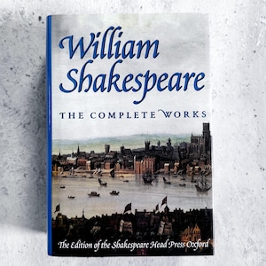 May include: A hardcover book titled "William Shakespeare The Complete Works." The cover features a blue title and a detailed illustration of a cityscape with boats on a river. The edition is from the Shakespeare Head Press Oxford.