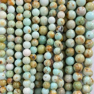 May include: A strand of round, green turquoise beads with brown and white marbling. The beads are approximately 6mm in diameter.