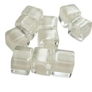 May include: A group of eight clear, translucent, square-shaped beads. The beads have a slightly frosted appearance.