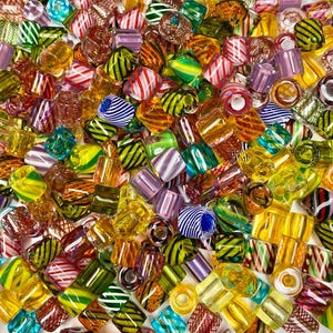 May include: A collection of colorful glass beads with various patterns and designs. The beads are made of clear, opaque, and translucent glass and feature stripes, swirls, and geometric shapes.