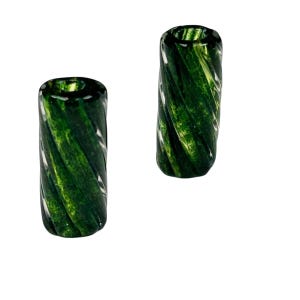 May include: Two green glass beads with a spiral design. The beads are cylindrical with a hole running through the center. The glass has a marbled appearance with shades of green and white.