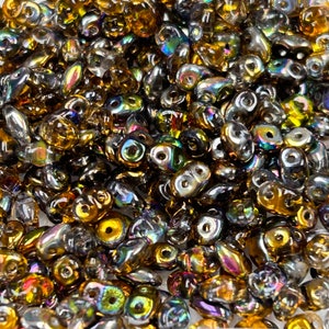 May include: A large quantity of iridescent glass beads in shades of brown and gold. The beads are teardrop shaped and have a glossy finish.