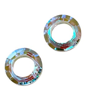 May include: Two iridescent clear glass rings with a beveled edge. The rings are about 1 inch in diameter.