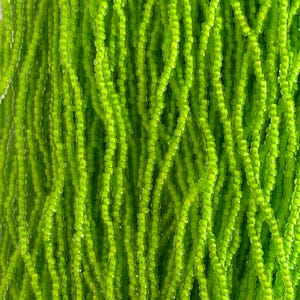 May include: Close-up of a vibrant green seed bead strand. The beads are small, cylindrical, and densely packed, creating a textured surface. The bright green color is consistent throughout the image, suggesting a uniform dye or material. Ideal for jewelry making and crafts.