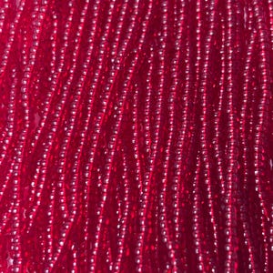May include: Close-up of strands of small, round, red beads. The beads are strung together, creating a textured, flowing pattern. The beads are a deep, vibrant red colour, and the light reflects off their surfaces, creating highlights.