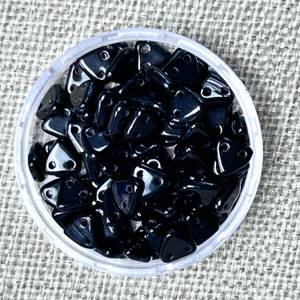 May include: A container of black triangle-shaped beads with two holes in each bead.