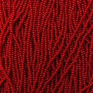 May include: Close-up of a mass of small, round, bright red beads. The beads are tightly packed together, creating a textured surface. The beads are uniform in size and shape, with a glossy finish. The overall effect is a vibrant, eye-catching display.