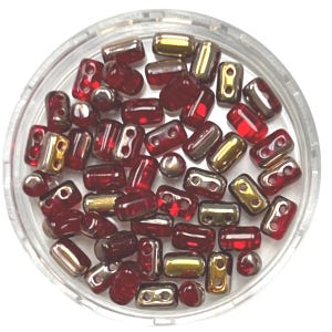 May include: A clear, round container filled with various red and gold beads. The beads are a mix of shapes, including small cylinders and double-holed rectangles. Some beads have a metallic gold finish, while others are a translucent red.
