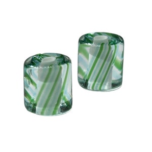 May include: Two clear glass candle holders with a white and green striped pattern.