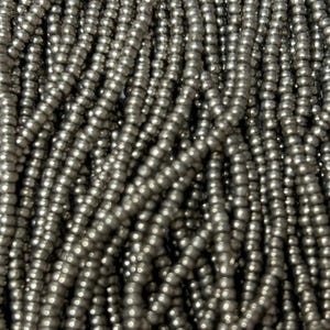 May include: Close-up of strands of small, round, silver beads. The beads are strung together, creating a textured surface. The beads have a metallic sheen and reflect light, giving them a shiny appearance. The beads are likely used for jewelry making or other crafts.