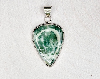 May include: A silver pendant with a green and white agate stone in a teardrop shape.