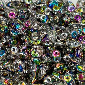 May include: A close-up of a pile of iridescent glass beads. The beads are clear with a rainbow sheen. They are small and round, and they are perfect for jewelry making.